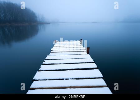 Neige sur la jetée et le lac brumeux, Stankow, est de la Pologne Banque D'Images