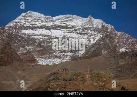 Les Alpes suisses qui s'élèvent à l'horizon avec leurs sommets enneigés se sont enfermées dans la neige blanche et les zones éparpillées d'herbe brune Banque D'Images