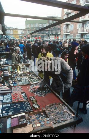 Londres 1977. Portobello Road avec ses magasins et ses marchés d'antiquités un samedi chargé. Une table d'un donneur de pièces est devant une femme qui les étudie de près. Kristoffersson réf. DV2 Banque D'Images