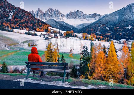 Touriste admirant la vue magnifique sur les collines enneigées du village de Santa Magdalena avec le pic de Seceda en arrière-plan. Spectaculaire scène automnale des Alpes Dolomites Banque D'Images