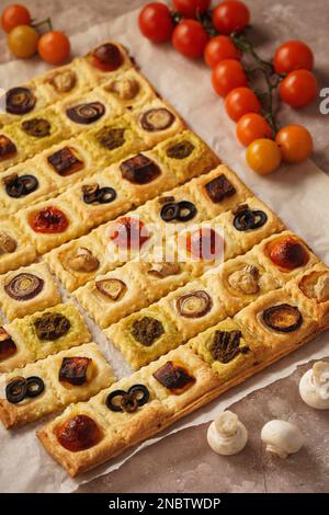 Mini-tourtes de pâte feuilletée avec tomates cerises, champignons, olives, fromage feta et oignon. Banque D'Images