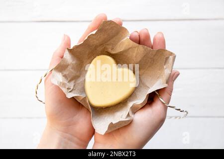 Femmes mains tenant et appliquant de la cire d'abeille faite à la main et beurre de karité crème hydratante solide pour les mains. Fait à la main avec tous les ingrédients naturels. Banque D'Images