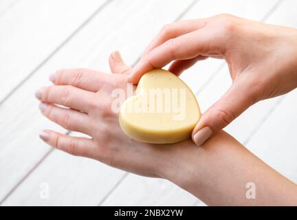 Femmes mains tenant et appliquant de la cire d'abeille faite à la main et beurre de karité crème hydratante solide pour les mains. Fait à la main avec tous les ingrédients naturels. Banque D'Images
