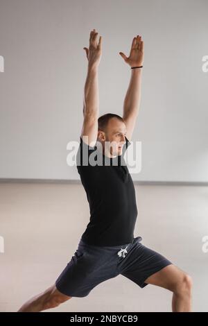 Un homme de construction athlétique fait du yoga dans la salle de gym sur un tapis. Banque D'Images