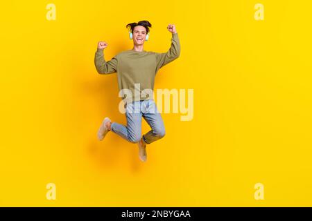 Portrait complet du corps de l'homme ravi surjoyé sautant élever les poings isolés sur fond jaune Banque D'Images