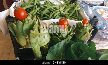 Pile d'artichaut vert avec tomates cerises exposées sur un marché agricole, Izmir, Turquie Banque D'Images