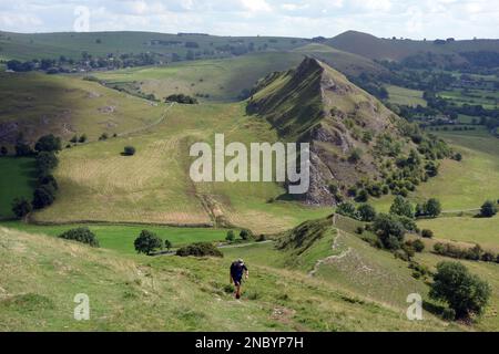 Homme marchant sur le sentier Ridge de Chrome Hill avec Parkhouse Hill en arrière-plan dans la Dove Valley, Peak District National Park, Angleterre, Royaume-Uni. Banque D'Images