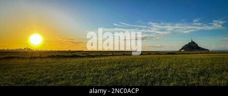 Une vue panoramique sur le soleil jaune vif qui brille sur la végétation luxuriante de la station balnéaire par le Mont Saint-Michel Banque D'Images