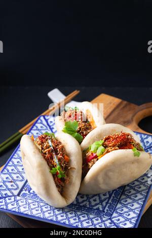 Concept alimentaire Buns Bao de bœuf bio faits maison ou Gua Bao dans une assiette carrée sur fond noir avec espace de copie Banque D'Images