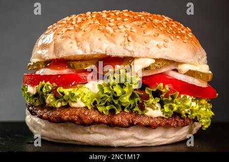 Hamburger aux oignons tomates concombre et laitue sur fond gris foncé. Banque D'Images