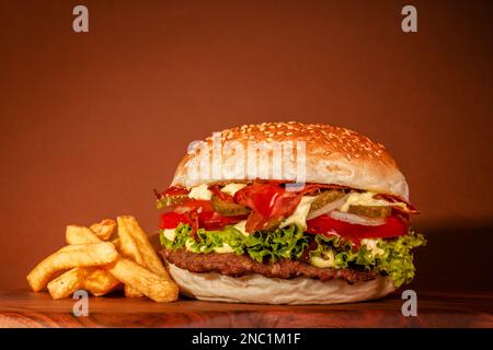 Hamburger au bacon avec oignons tomates concombres laitue et frites. Photo de restauration rapide Banque D'Images