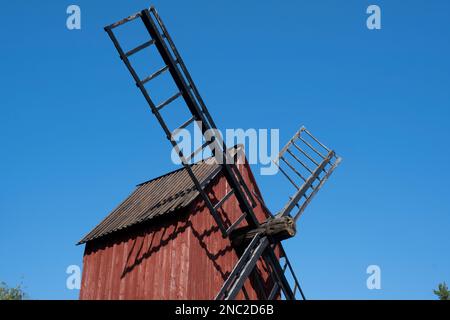 Helsinki / Finlande - 14 AOÛT 2022 - et ancien moulin à vent rouge avec des lames de bois contre un ciel bleu vif Banque D'Images