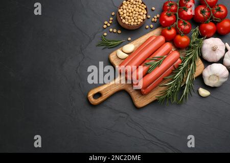 Saucisses végétariennes fraîches et légumes crus sur une table noire, plat. Espace pour le texte Banque D'Images