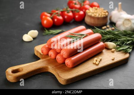 Saucisses et légumes frais et crus végétariens sur table noire Banque D'Images