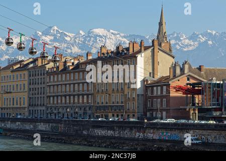 GRENOBLE, FRANCE, 8 février 2023 : le téléphérique Bubbles part de la ville vers la colline de la Bastille, avec les montagnes enneigées de la chaîne de Belledonne dans le bac Banque D'Images