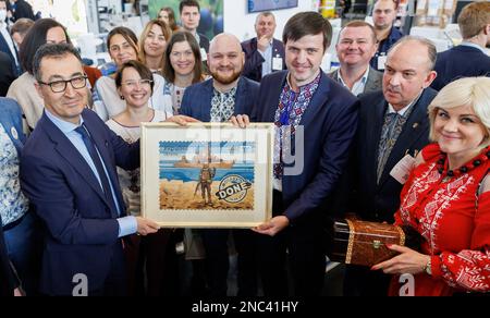 Nuremberg, Allemagne. 14th févr. 2023. Le ministre fédéral de l'Agriculture CEM Özdemir (l, Bündnis 90/Die Grünen) tient une photo qu'il a reçue en cadeau lors d'une visite du salon Biofach à côté des employés du pavillon de l'Ukraine. De 14 février à 17, 2023, au salon mondial de l'alimentation biologique Biofach et au salon des cosmétiques naturels Vivaness, 2 765 exposants de 95 pays présenteront des produits de l'industrie des aliments biologiques et des cosmétiques naturels. Credit: Daniel Karmann/dpa/Alay Live News Banque D'Images