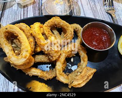 Une assiette de calamars frits avec sauce aux fruits de mer et citron. Banque D'Images