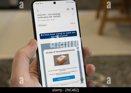 Main tenant un smartphone avec un faux e-mail de phishing de nom de compagnie de livraison de colis de fraudeurs visant à obtenir des données et des informations personnelles Banque D'Images