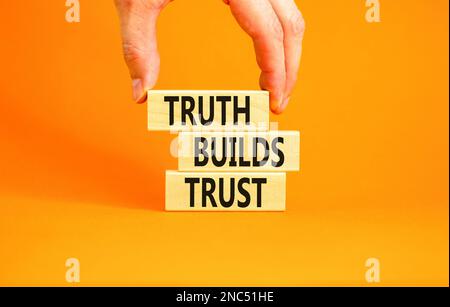 La vérité crée un symbole de confiance. Concept Words Truth construit la confiance sur des blocs de bois sur une belle table orange fond orange. Main d'homme d'affaires. Entreprise Banque D'Images