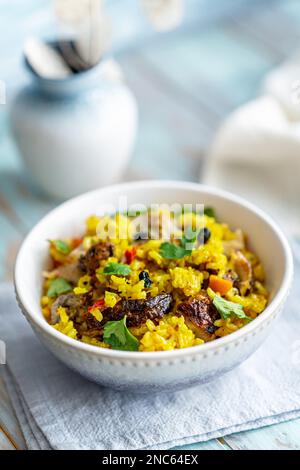 Riz pilaf au poulet dans un bol sur une table en bois bleu. Mise au point sélective, mise au point faible peu profonde Banque D'Images