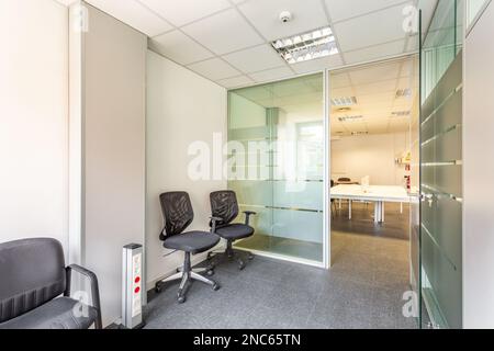 Bâtiment abandonné d'un propriétaire insolvable avec un intérieur dans un style de bureau simple. Bureaux, à gauche et à droite, avec des cloisons en verre et un petit soleil Banque D'Images