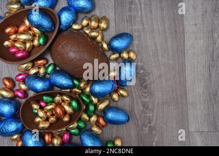 Pile ou groupe de plusieurs couleurs et différentes tailles d'oeufs de pâques au chocolat enveloppés de papier d'aluminium coloré dans le rose, le bleu, l'or et le vert. Banque D'Images