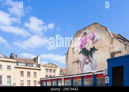 Art mural peint sur le côté du bâtiment à bristol Royaume-Uni, représentant une personne tenant un bouquet de fleurs roses roses Banque D'Images
