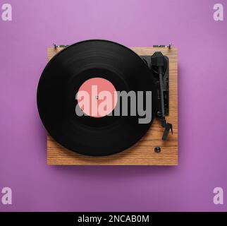 Platine moderne avec disque vinyle sur fond violet, vue de dessus Banque D'Images