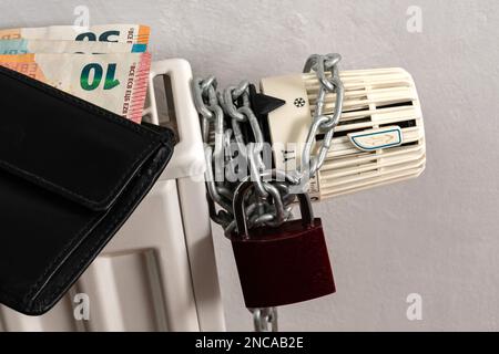 Portefeuille avec billets en euros sur radiateur de chauffage central, fermé sur une chaîne avec n'importe quelle serrure. Gros plan. Banque D'Images