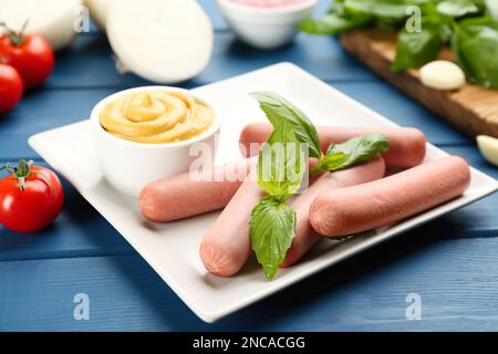 Saucisses végétariennes fraîches et crues au basilic et sauce sur table en bois bleu Banque D'Images