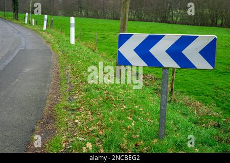 Route et signalisation routière indiquant un virage sur la route. Concept de sécurité routière. Une flèche indiquant un virage à gauche sur la route. Banque D'Images