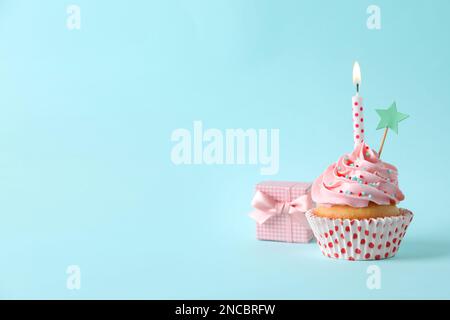 Gâteau d'anniversaire avec bougie, boîte-cadeau et surmatelas sur fond bleu clair. Espace pour le texte Banque D'Images