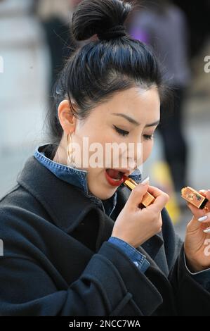 14th février 2023. Londres, Royaume-Uni. Une femme asiatique mettant un rouge à lèvres à Whitehall, Londres, Royaume-Uni. Banque D'Images