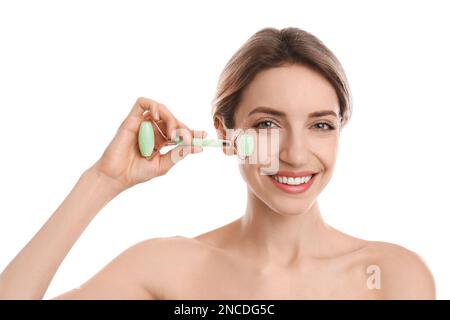 Jeune femme utilisant le rouleau de visage de jade naturel sur fond blanc Banque D'Images