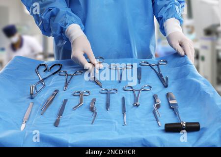 Infirmière près de la table avec différents instruments chirurgicaux dans la salle d'opération, en gros plan Banque D'Images