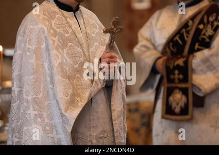 Prêtre avec la croix menant la cérémonie de baptême dans l'église, clôture Banque D'Images