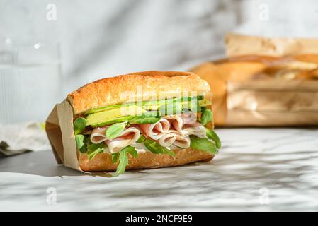 sandwich à l'avocat et à la parme. sandwich baguette dans un emballage artisanal pour livraison Banque D'Images