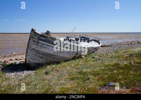 Vue de face d'un vieux bateau en bois détruit et coincé sur un rivage rocheux, au nord d'Arviat, Nunavut, Canada Banque D'Images