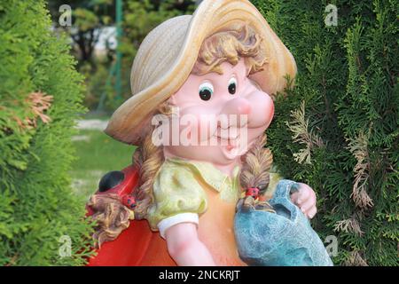 La figure de jardin est une femme naine proche entre les arbres verts, le gnome a un grand sourire Banque D'Images