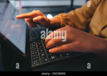 Un gros plan d'une main de femme qui commande un ordinateur portable à écran tactile dans un cadre professionnel Banque D'Images
