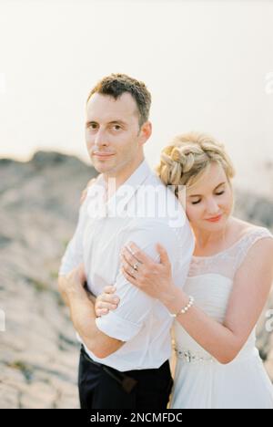 La mariée épouse épouse la groom de derrière avec sa tête reposant sur son épaule. Portrait Banque D'Images