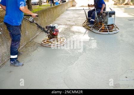 Deux types de truelle électrique auto-nivelante avec moteur à gaz ont des roues avec patins, plaque et il la conduit en cercles lissage de surface sur conc Banque D'Images
