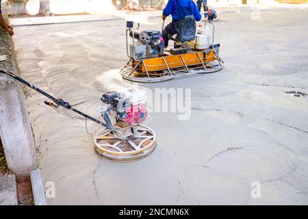 Deux types de truelle électrique auto-nivelante avec moteur à gaz ont des roues avec patins, plaque et il la conduit en cercles lissage de surface sur conc Banque D'Images
