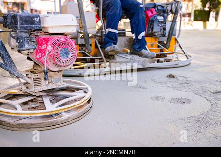 Deux types de truelle électrique auto-nivelante avec moteur à gaz ont des roues avec patins, plaque et il la conduit en cercles lissage de surface sur conc Banque D'Images