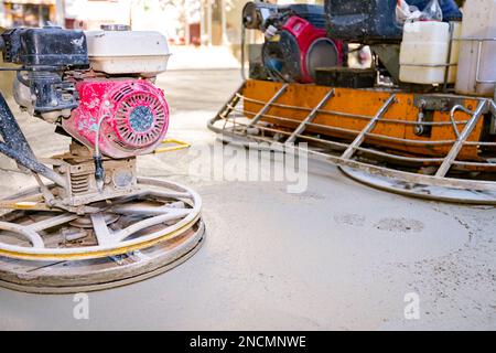 Deux types de truelle électrique auto-nivelante avec moteur à gaz ont des roues avec patins, plaque et il la conduit en cercles lissage de surface sur conc Banque D'Images