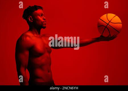L'état d'esprit est ce qui vous aide à dépasser vos limites. Photo filtrée rouge d'un jeune sportif posant avec un ballon de basket dans le studio. Banque D'Images