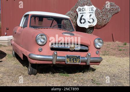 Une vieille petite voiture urbaine abandonnée dans une ferme, c'est une Nash Metropolitan rouge Banque D'Images