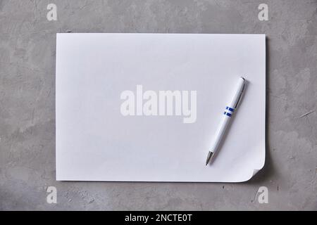 Feuille de papier blanc avec stylo à bille sur fond gris. Copier l'espace Banque D'Images