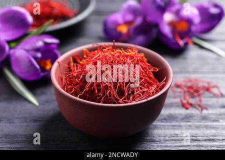 Safran séché dans un bol et fleurs de crocus sur une table en bois noir, gros plan Banque D'Images