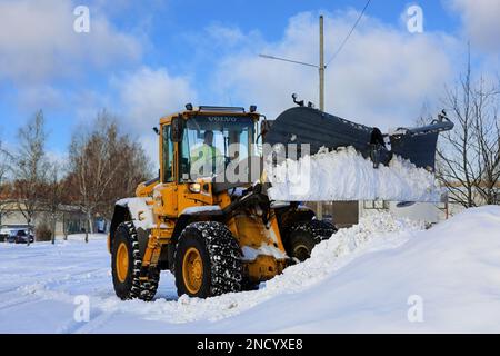 Déneigement avec une chargeuse sur pneus Volvo L70E équipée d'un chasse-neige après une chute de neige par jour d'hiver. Salo, Finlande. 11 février 2023. Banque D'Images